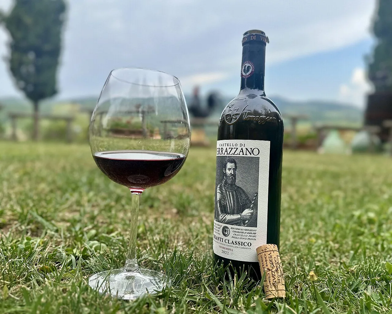 Una bottiglia di Chianti Classico e un calice di vino rosso in un prato